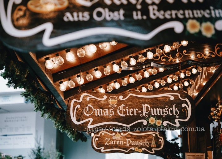 Hölzerner Weihnachtsmarktstand mit Lichterketten, Tannengirlande und Punsch-Schildern