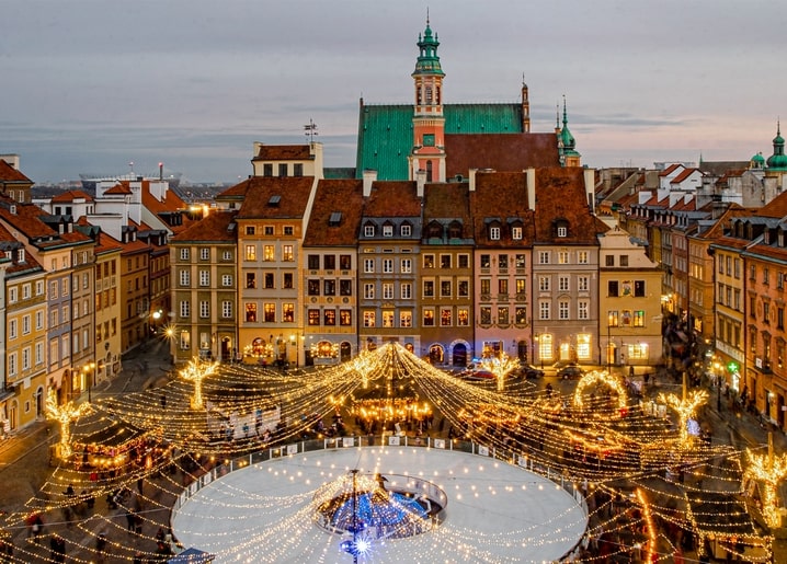 Aerial view of a European old town square lit up for a Christmas market with an ice rink