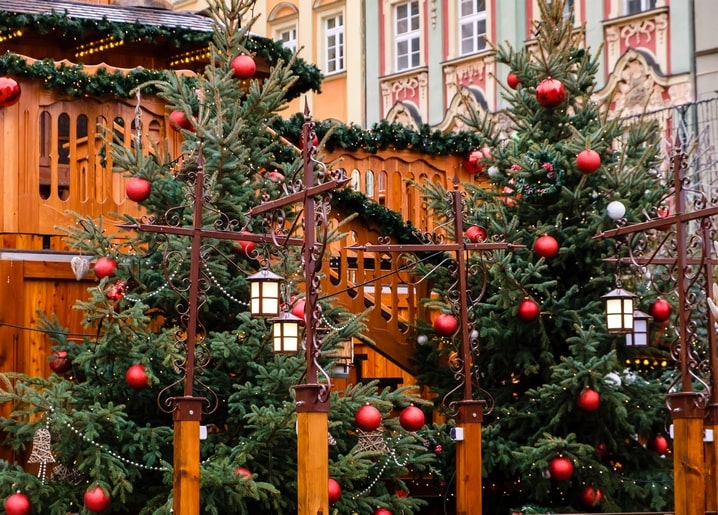 Geschmückte Tannen mit roten Kugeln und Laternen an einem Weihnachtsmarktstand