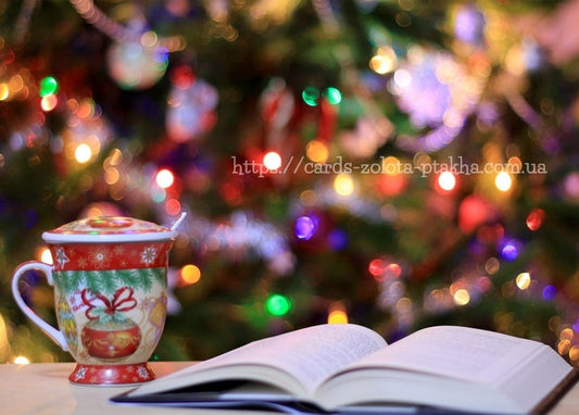 Weihnachtstasse mit Löffel neben aufgeschlagenem Buch, verschwommene Baumlichter im Hintergrund