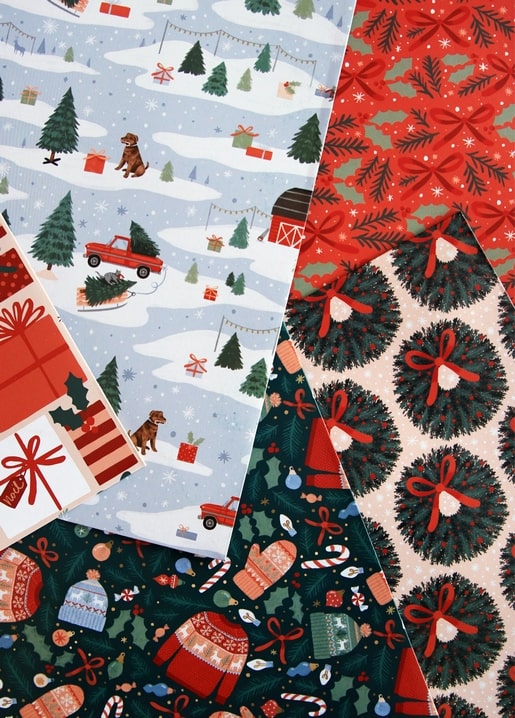 Flat lay of Christmas wrapping paper patterns with pines, wreaths, and sweaters