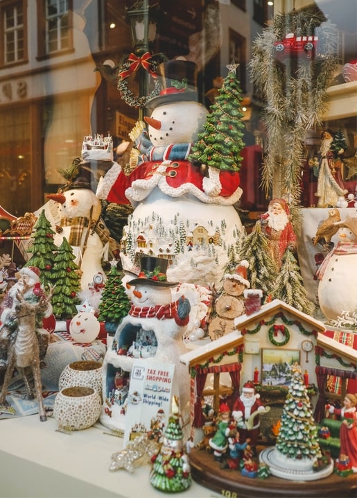 Weihnachtsschaufenster mit Schneemann- und Weihnachtsmannfiguren, Tannen und beleuchtetem Nussknacker-Haus
