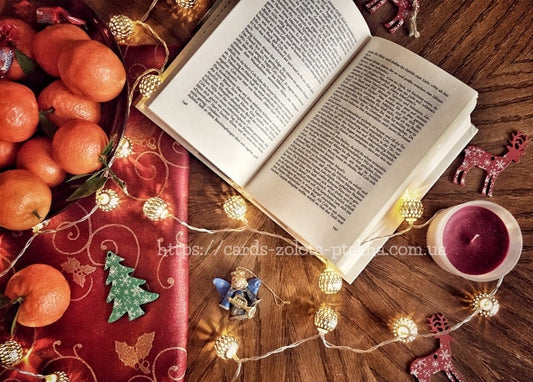Weihnachtliches Stillleben mit Buch, Mandarinen, Lichterkette und weinroter Kerze