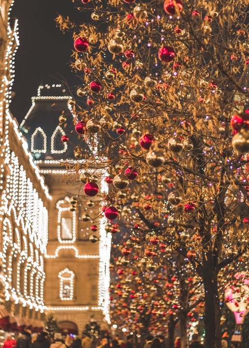 String lights and red-gold Christmas baubles glowing on a European street at night