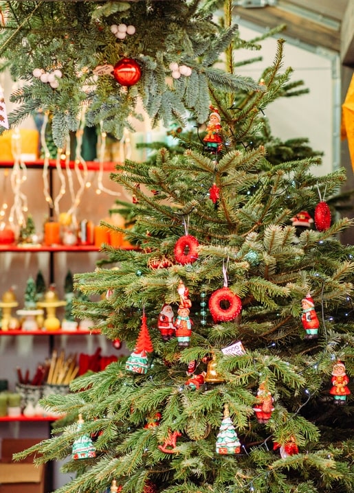 Weihnachtsbaum mit roten Kugeln und Nikolausfiguren im Laden