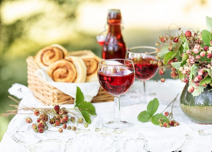 Булочки з корицею, лісова полуничка та келихи ягідного напою на столі