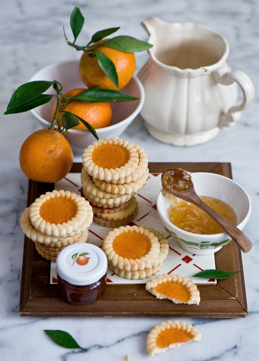 Marmeladenkekse mit einer Schale frischer Mandarinen und Zitrusmarmelade