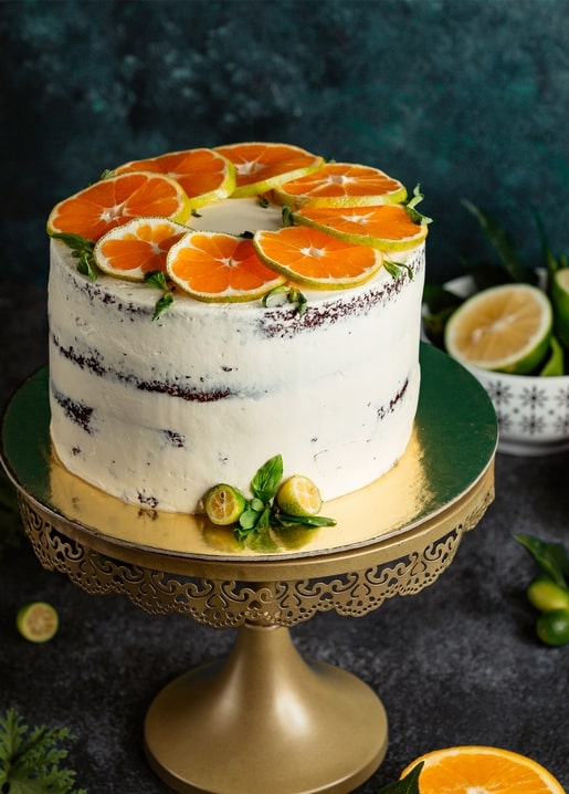 Naked Cake mit Orangen- und Limettenscheiben, Minze und Kumquats auf goldenem Ständer