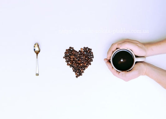Herz aus Kaffeebohnen, Löffel und Hände mit einer Tasse auf weißem Hintergrund