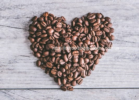 Kaffeebohnen zu einem Herzen auf einer verwitterten Holzplatte drapiert