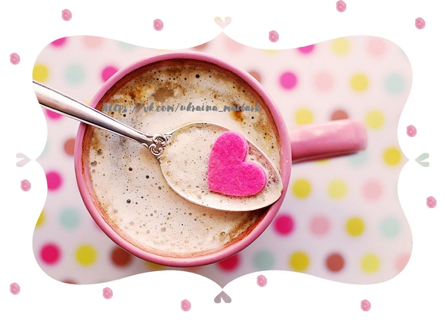 Frothy coffee in a pink mug with a silver spoon and a tiny felt heart, polka-dot background