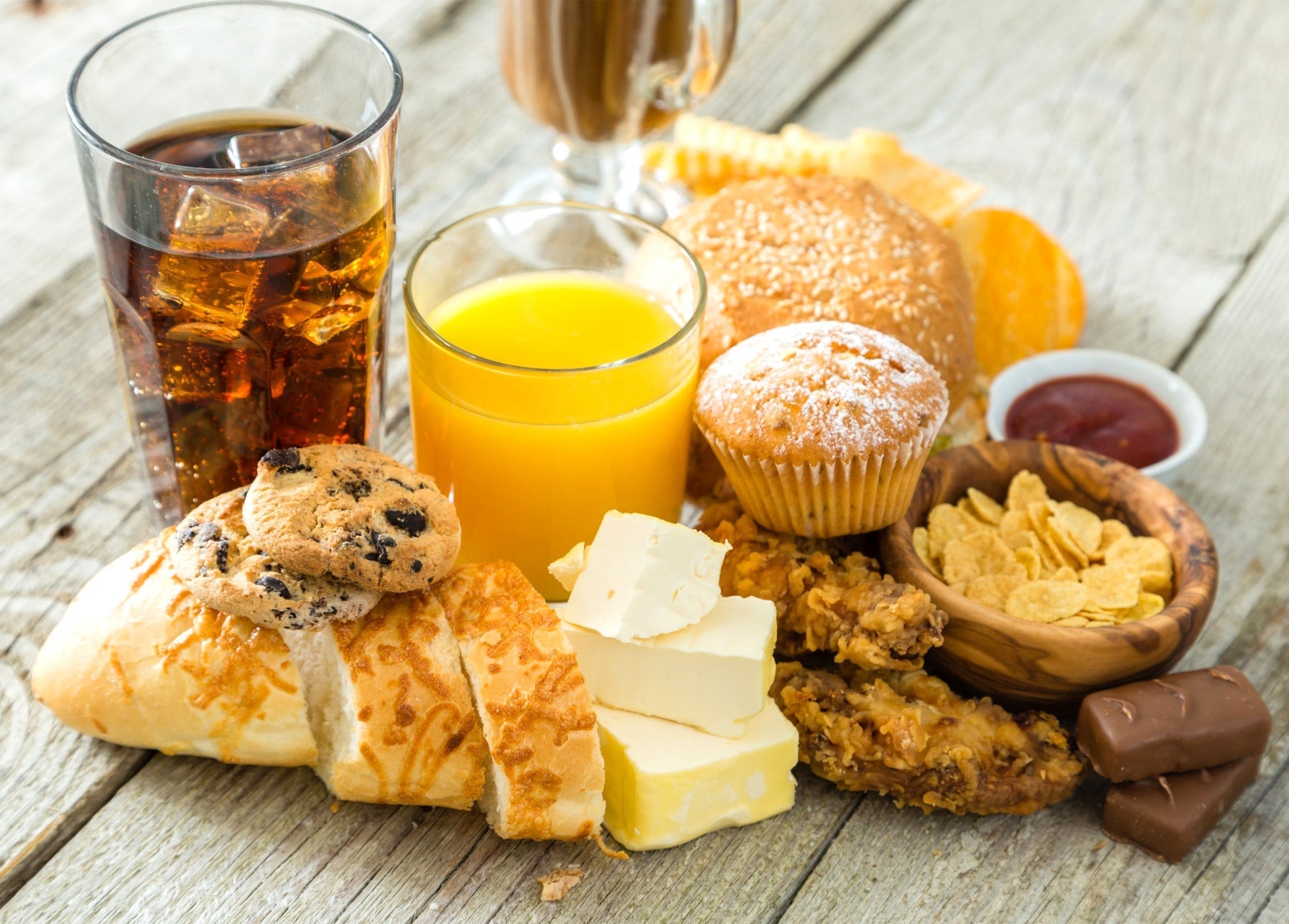Tisch mit Cola, Orangensaft, Kaffee, Sesambrötchen, Muffin, Keksen, Baguette und Schokolade