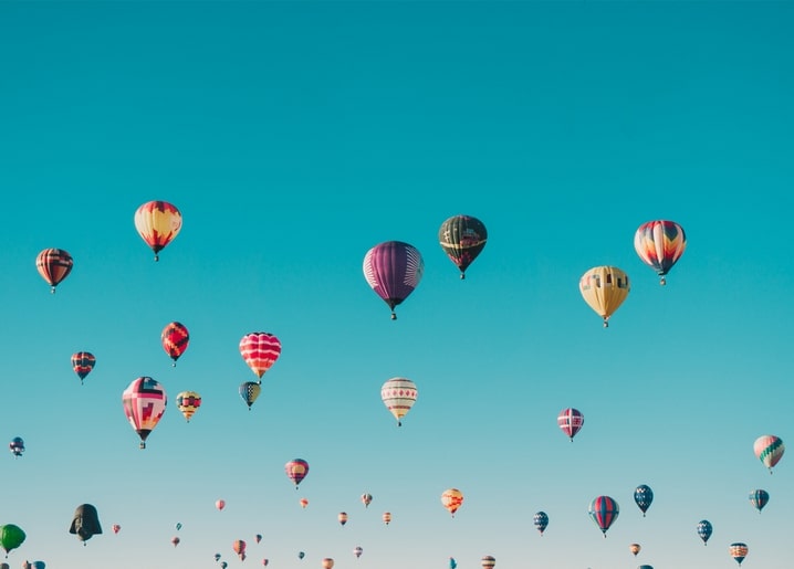 Dutzende bunte Heißluftballons vor einem satten blauen Himmel