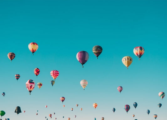 Dutzende bunte Heißluftballons vor einem satten blauen Himmel