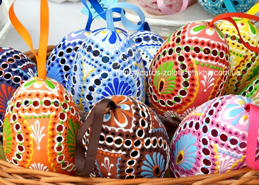 Wicker basket filled with colorful hand-painted pysanky Easter eggs tied with ribbons