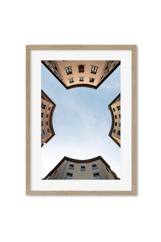 Upward view of four building façades converging toward the sky