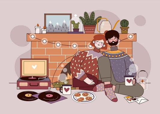 Couple cuddling by a fireplace with cocoa, cookies and a record player