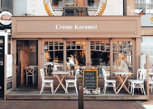 Рожевий фасад кафе Crème Karamel з вуличними столиками та стільцями