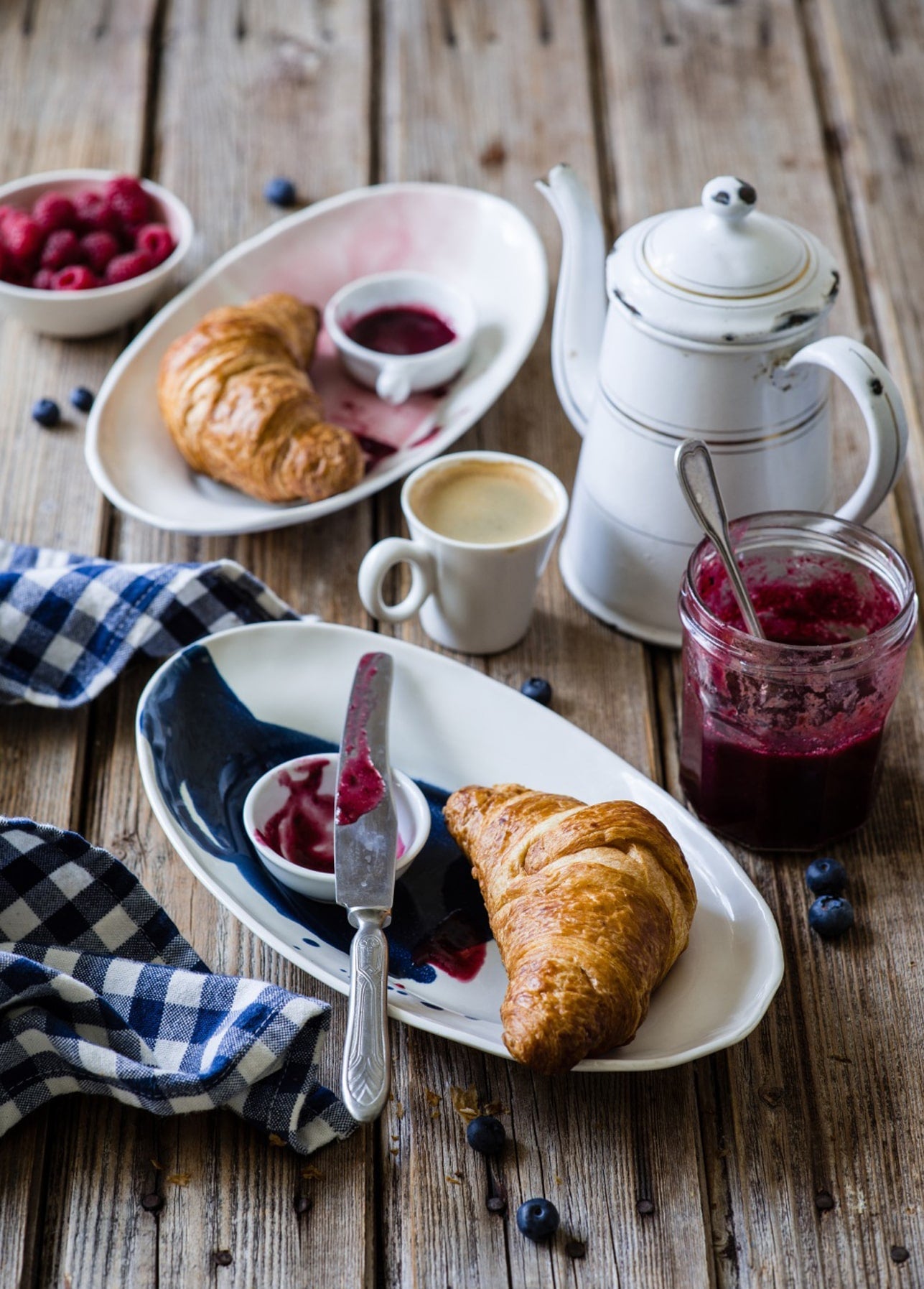 Two croissants with berry jam, fresh raspberries, espresso and a vintage enamel coffee pot