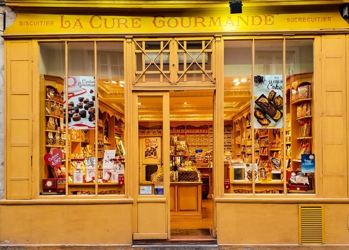 Gelbes Schaufenster der Konditorei La Cure Gourmande in der Abenddämmerung