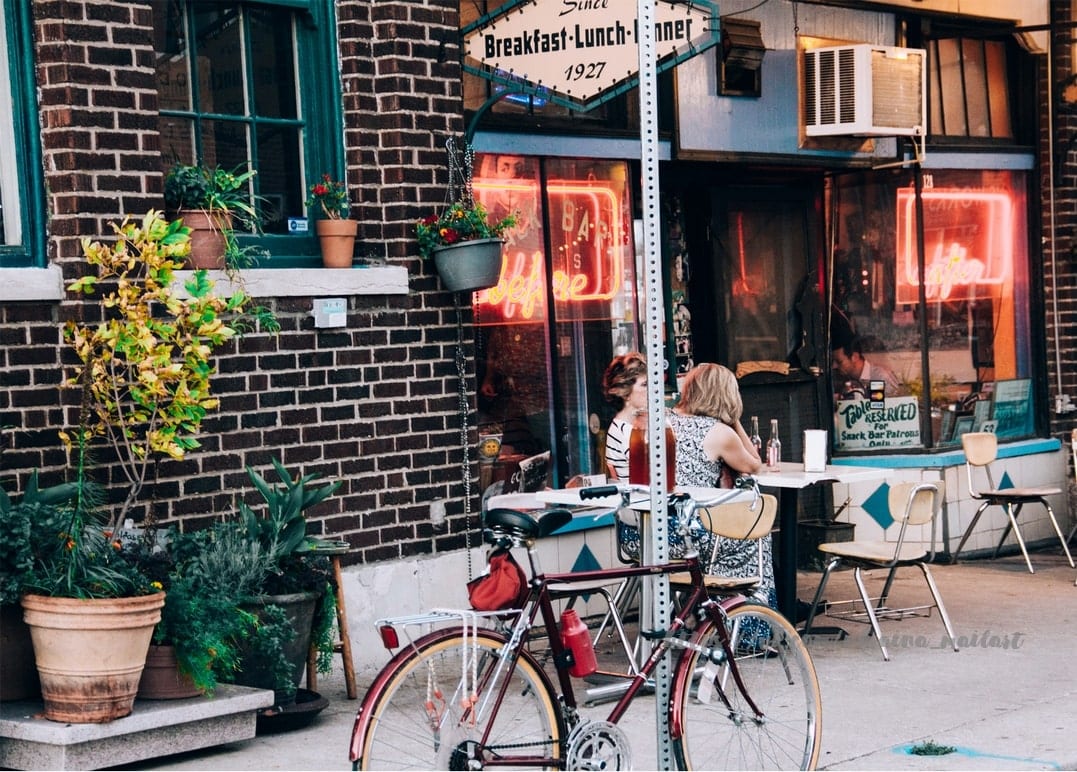 Backstein-Diner mit leuchtendem Neon-Schild Coffee und Vintage-Fahrrad davor