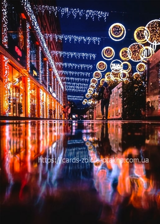 Illuminated night street in Dnipro with string lights and a couple walking on wet pavement