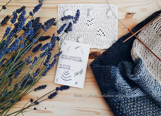 Getrockneter Lavendel, ein handgezeichnetes Zine und Stricknadeln auf Holztisch