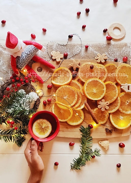 Getrocknete Orangenscheiben, Zimt und Lebkuchen neben einer Tasse Glühwein