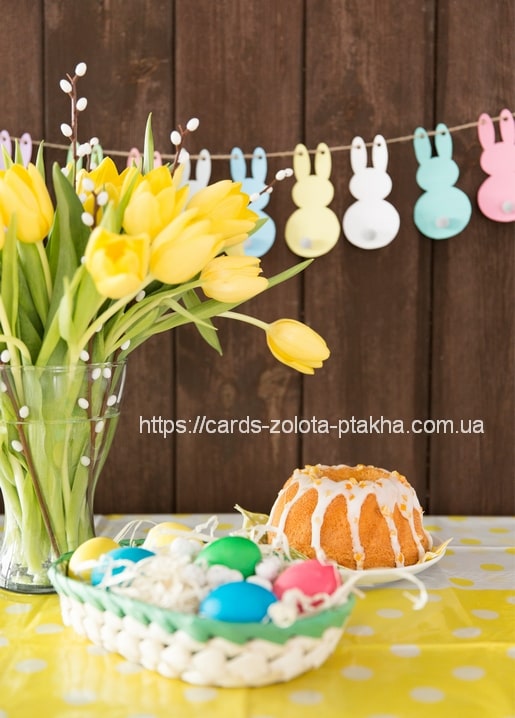 Easter cake, painted eggs and yellow tulips with a bunny garland