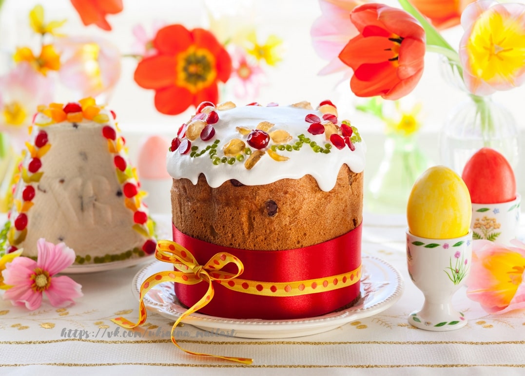 Traditional Easter cake with red ribbon, egg cup, and tulip flowers on a festive table