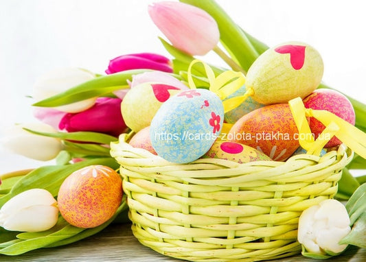 Wicker basket of pastel patterned Easter eggs nestled among pink and white tulips