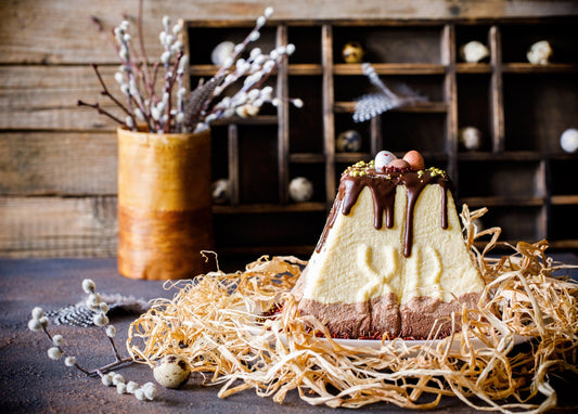 Chocolate-drizzled Easter paska topped with quail eggs in a straw nest, pussy willow nearby