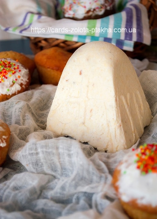 Easter paska loaf on cheesecloth surrounded by sprinkle-topped cupcakes