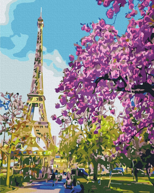 Eiffel Tower framed by branches of pink and purple blossoms in a Paris park