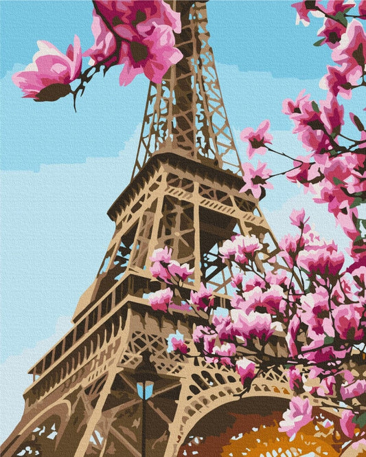 Eiffel Tower seen through blooming pink cherry blossom branches against a blue sky