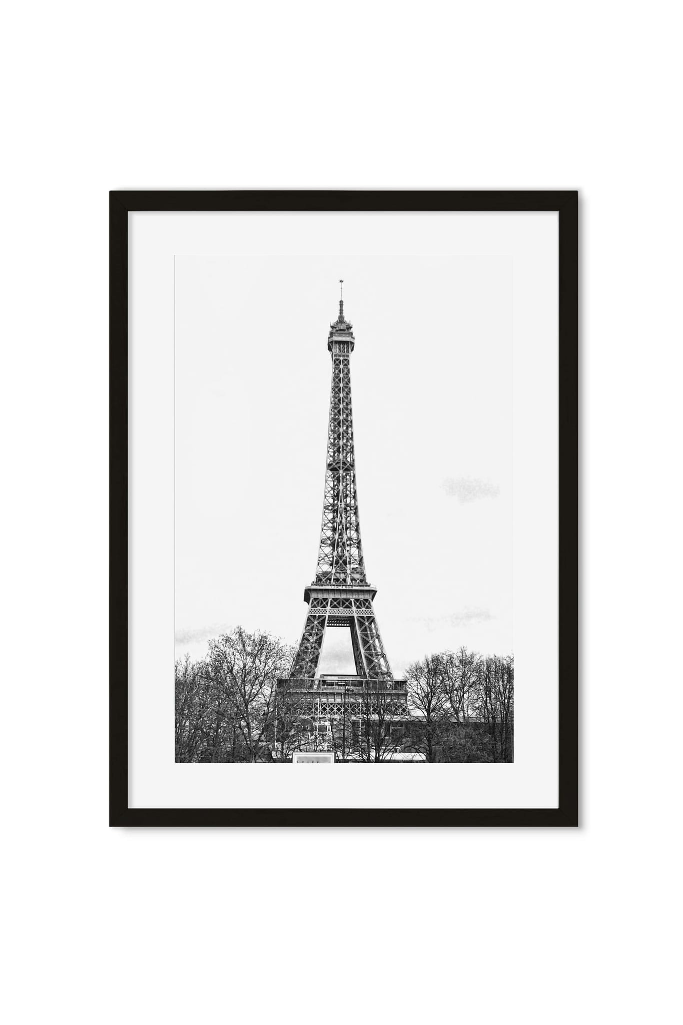 Black-and-white photo of the Eiffel Tower rising above bare winter trees