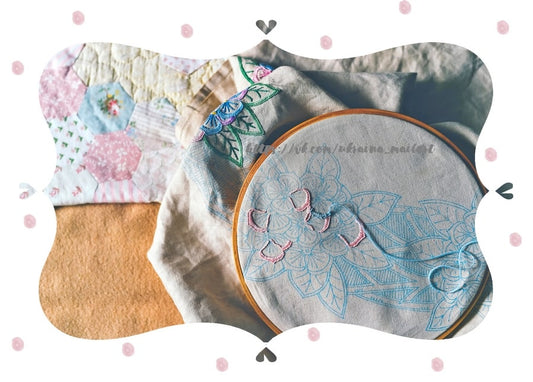 Stickrahmen mit halb fertigem blauen Blumenmuster auf einer Patchworkdecke