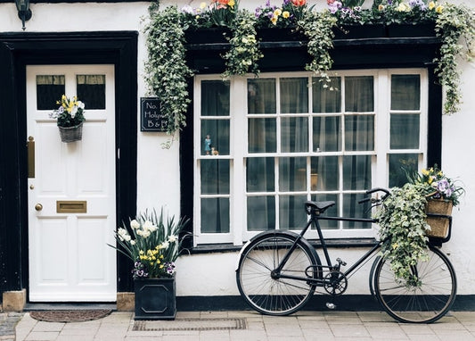 Weißes Cottage mit Tulpenkästen und einem Fahrrad mit Blumen