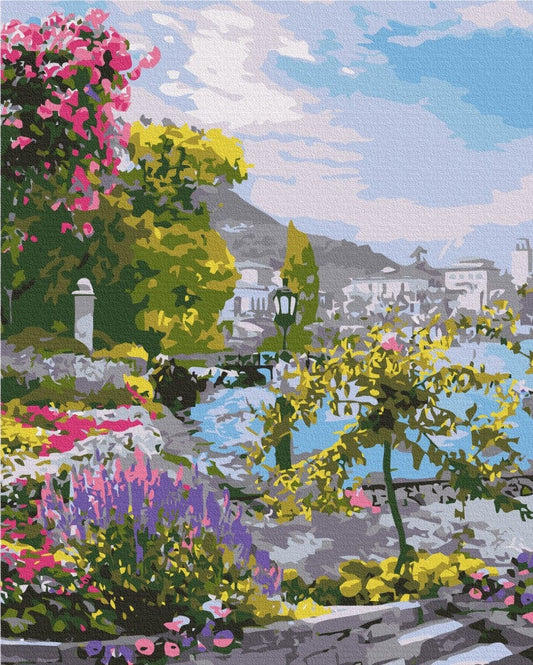 Pink and purple flowers on a stone balustrade overlooking a coastal town and mountains