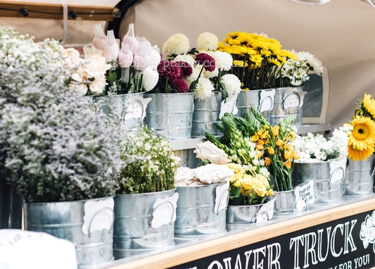 Blumenstand mit Metalleimern voller Chrysanthemen, Rosen, Sonnenblumen und Schleierkraut