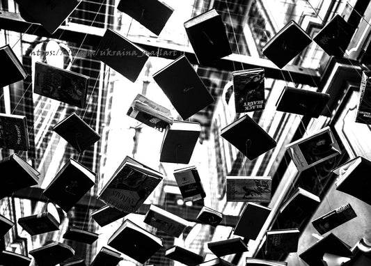 Black-and-white photo of hundreds of books suspended on strings above a stairwell