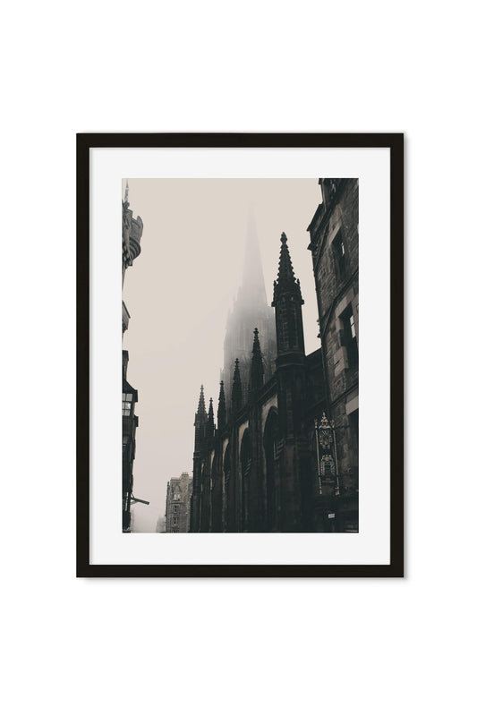 Black-and-white photo poster of a gothic cathedral spire in fog above an old street