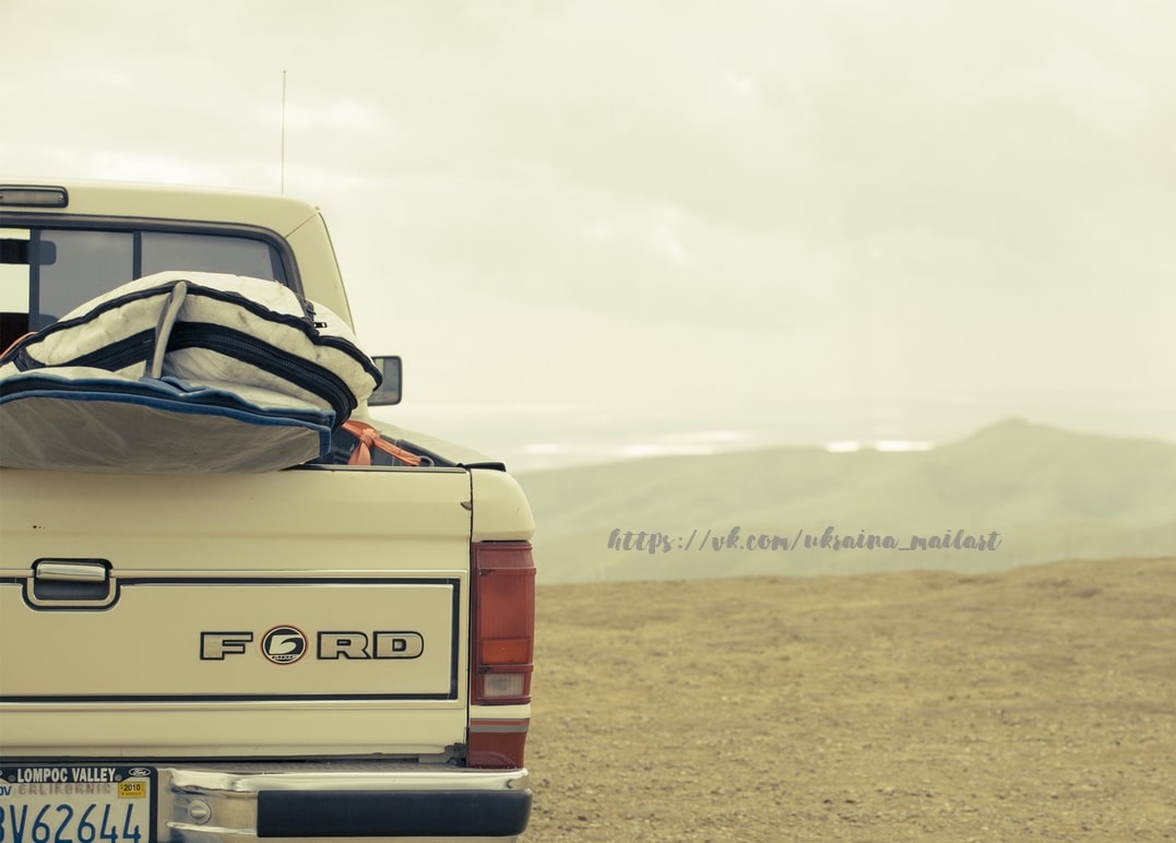Ladefläche eines alten Ford-Pickups mit Surfboard vor Wüstenbergen