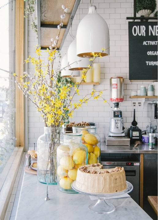 Forsythienzweige, eingelegte Zitronen und Walnusskuchen auf einer Café-Theke mit Pendelleuchten