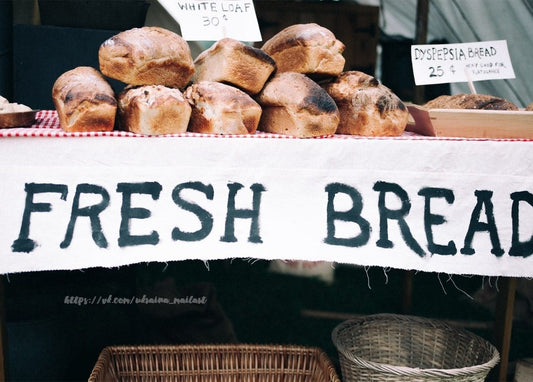 Frische Brotlaibe über einem handgemalten „FRESH BREAD“-Marktbanner