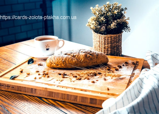 Runder Brotlaib mit Kaffee, Kornähre und Trockenblumen auf einem Holzbrett