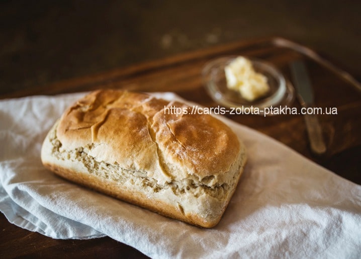 Frisches Weißbrot auf Leinentuch, im Hintergrund Butter und ein Messer