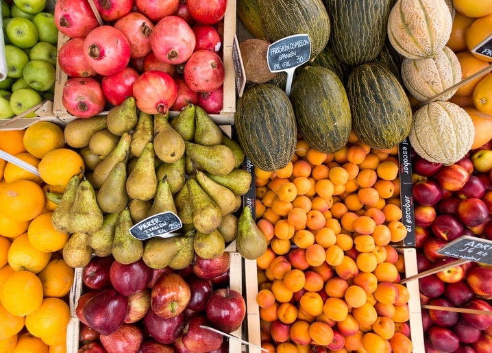 Granatäpfel, Melonen, Birnen und Aprikosen an einem bunten Marktstand