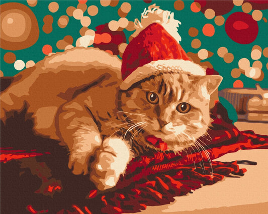 Rote getigerte Katze mit Weihnachtsmütze liegt auf rotem Lametta vor türkisem Lichterbokeh