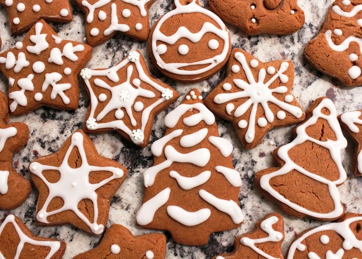 Star, tree, and ornament-shaped gingerbread cookies decorated with white icing on marble